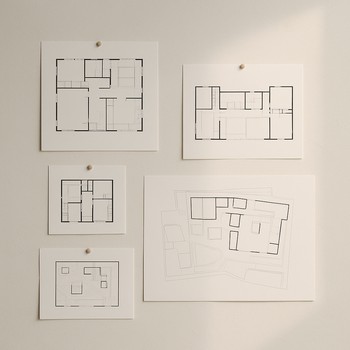 Studiya divarında sancaqla tutulan plan eskizləri və fotolar
